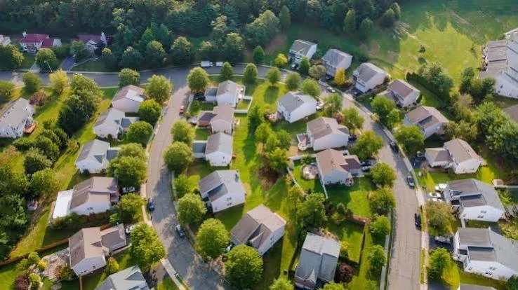 Aerial view of a neighborhood of homes with green lawns and trees.